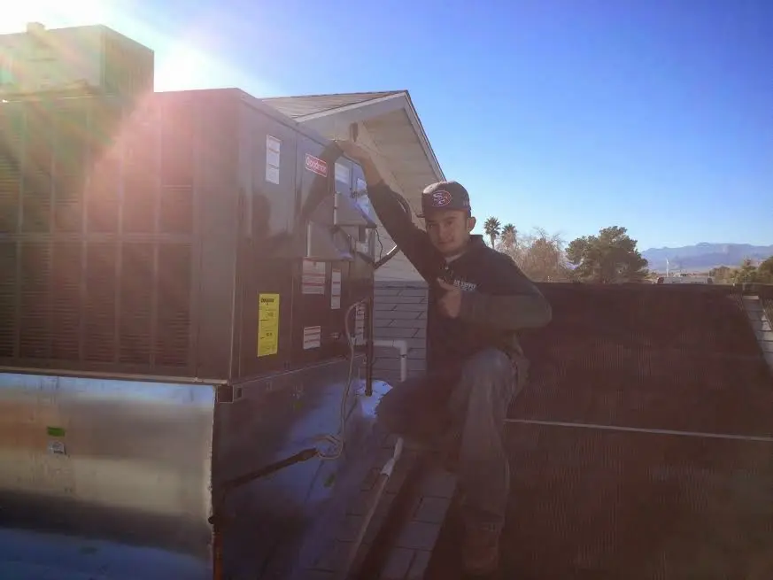 HVAC technician performing AC Tune-Up on a rooftop unit in Lee
